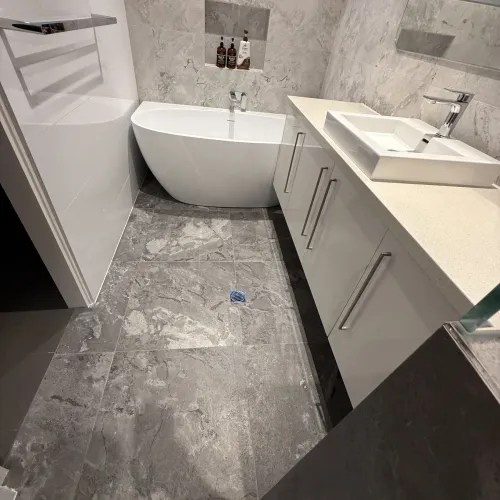 Bathroom renovation with a freestanding bath and dark stone floor tiling
