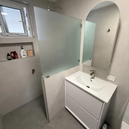 Bathroom renovation with a frosted glass shower divider and floating vanity