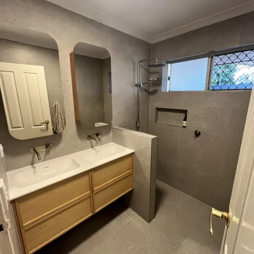 Bathroom renovation with dual round mirrors, a timber vanity and grey stone tiling