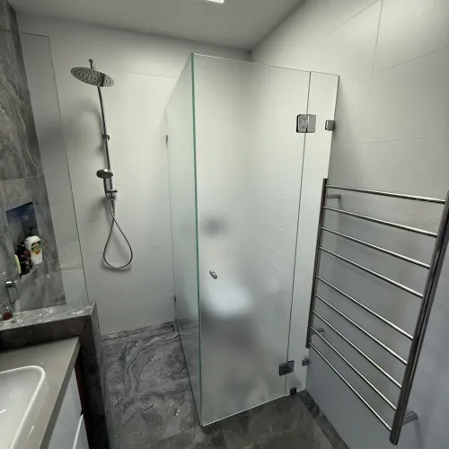 Walk-in shower renovation with a rain shower head, heated towel rail and grey stone tiling