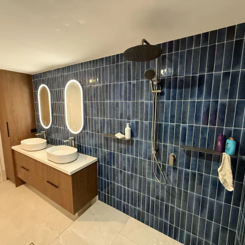 Bathroom renovation with dual backlit mirrors, a rain shower and navy feature tiling