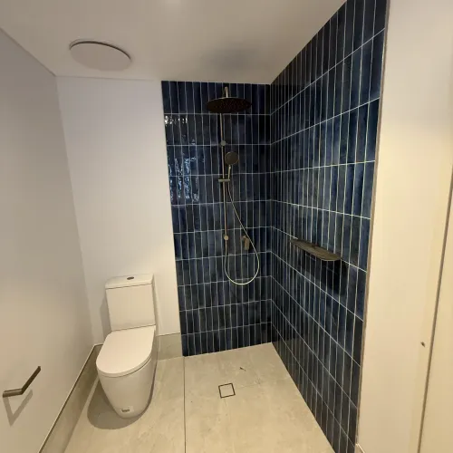 Walk-in shower renovation with a built-in niche and navy feature tiling