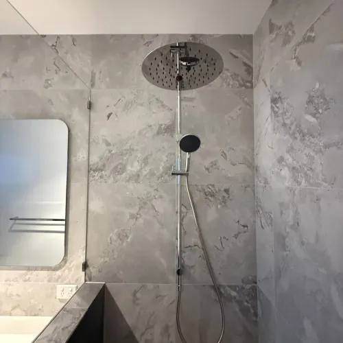 Close-up of a rain shower head against grey stone tiling