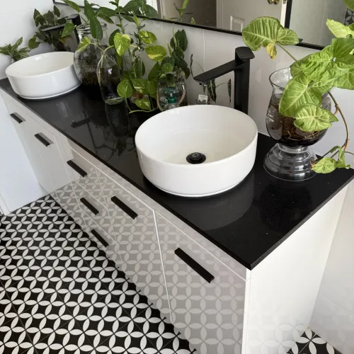 Bathroom vanity with dual vessel sinks, black benchtop and patterned tile flooring