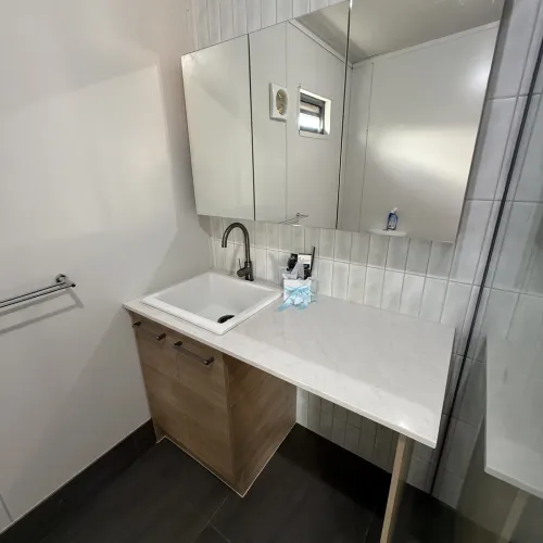 Bathroom renovation with subway tiling, a timber vanity and glass shower divider